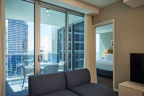 Habitación de hotel moderna con un amplio ventanal corredero que da a un balcón con vistas a la ciudad.