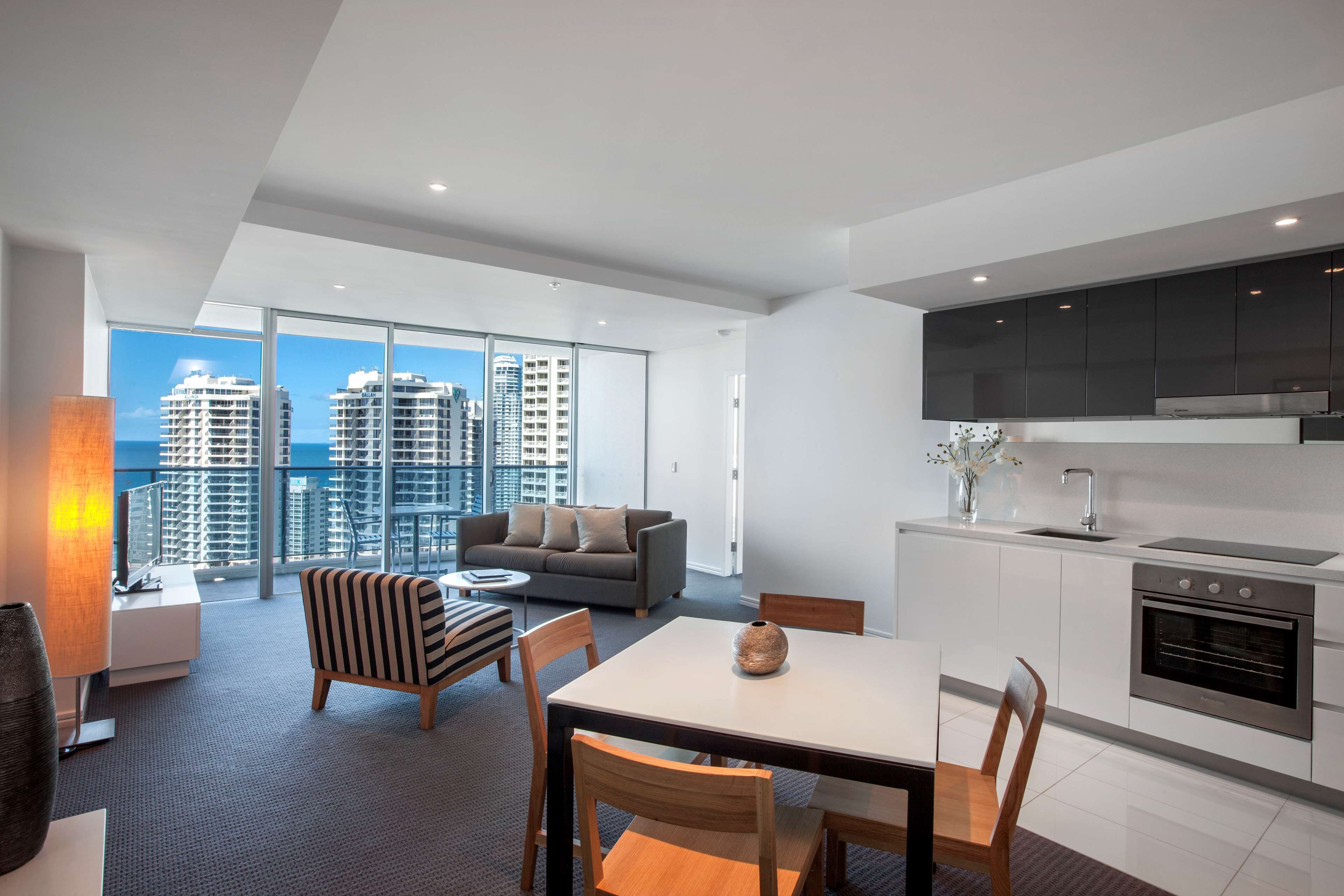 Un appartement moderne comprenant un coin repas, une cuisine et un grand balcon offrant une vue sur la ville.