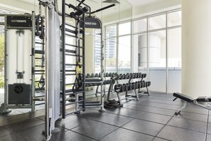 A gym with weightlifting equipment, dumbbells, and a squat rack.