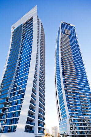 Two high-rise buildings with a modern architectural design, featuring numerous windows and balconies.