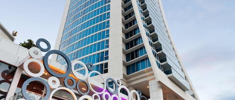 A modern high-rise building with a curved facade and a series of circular decorative elements at the base.