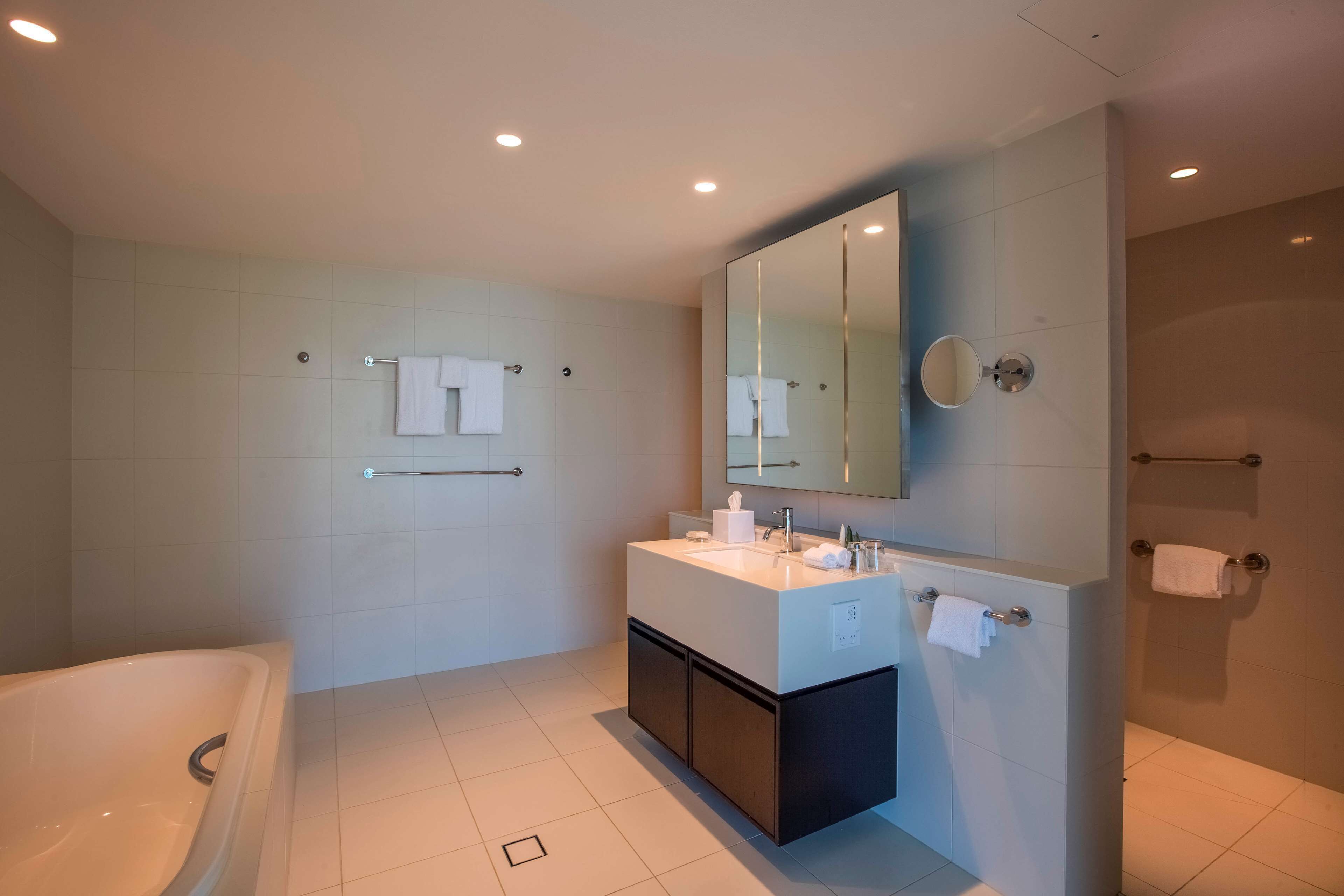 Un baño moderno con bañera, tocador con espejo y zona de ducha.