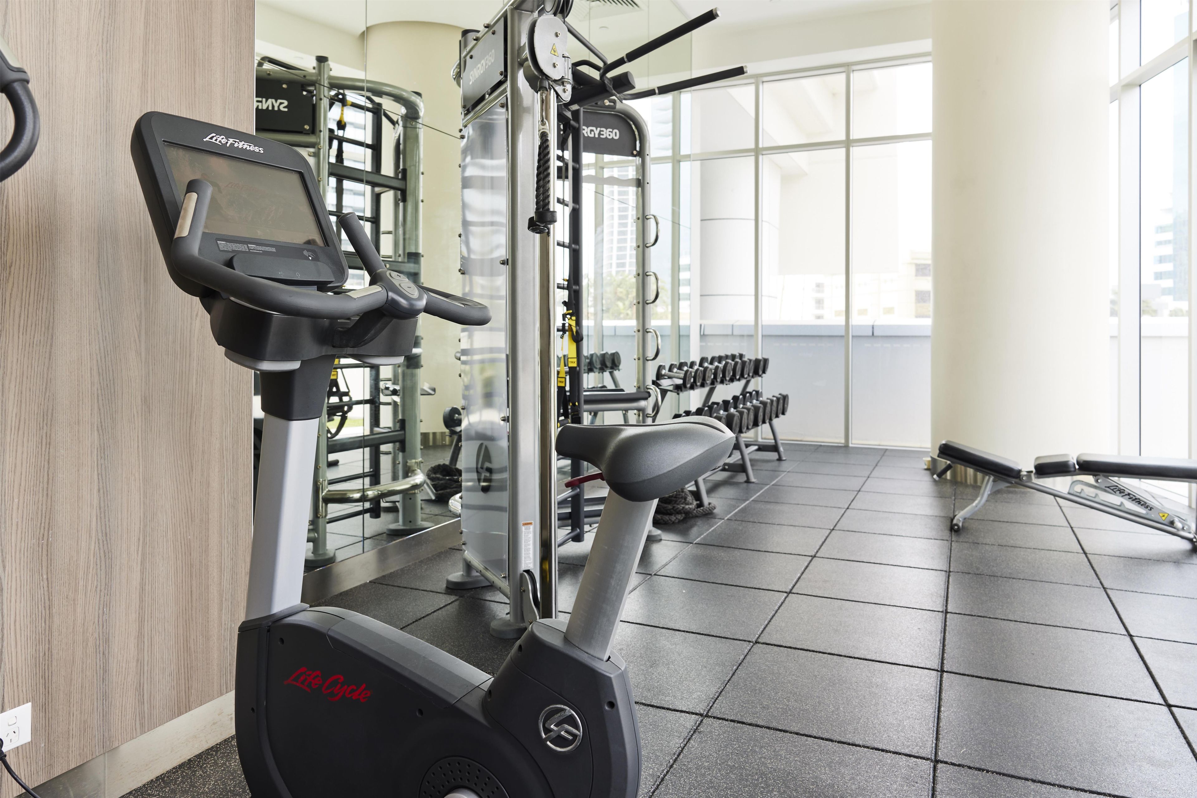 A gym with cardio equipment, weight machines, and dumbbells.