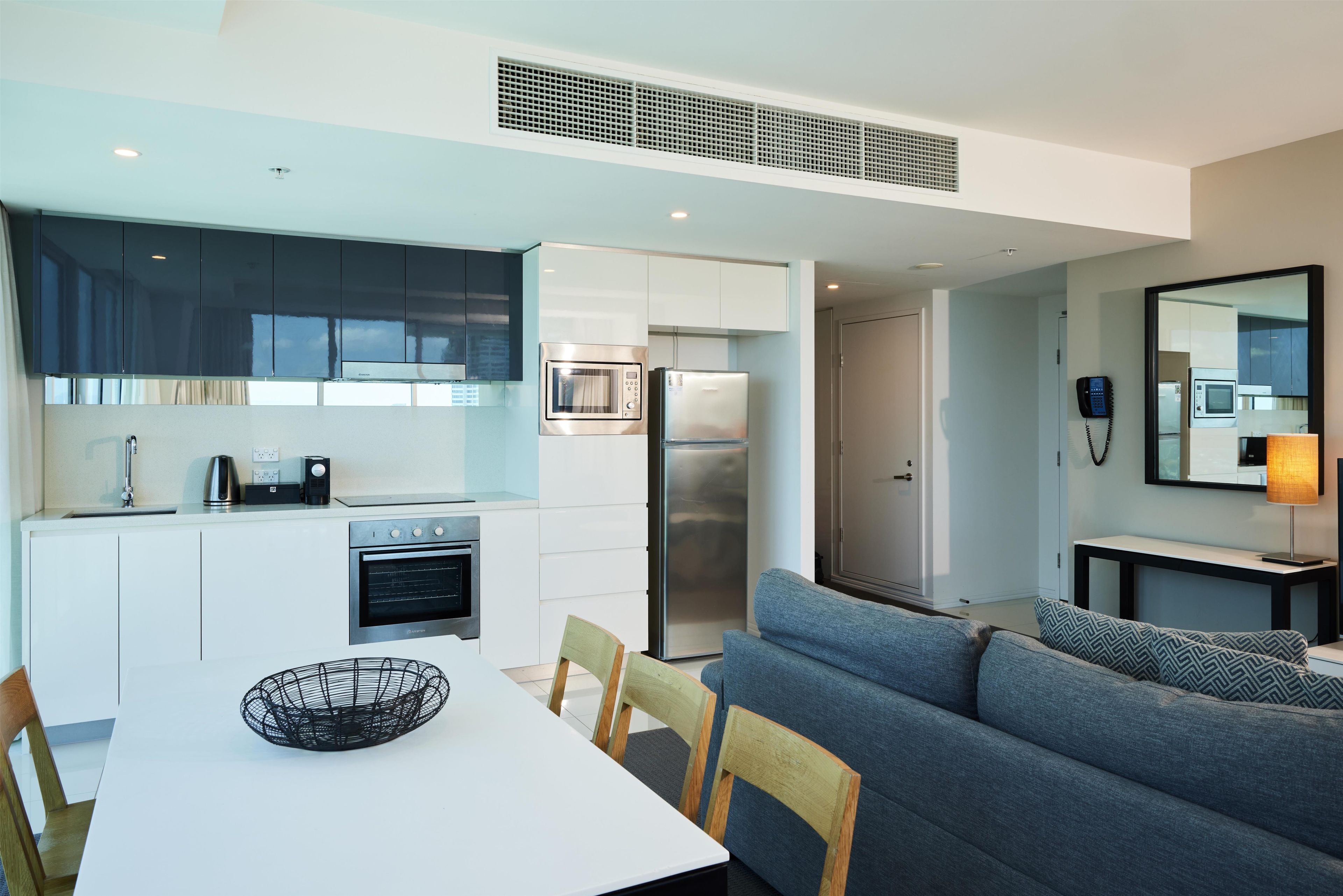 A modern kitchen with a dining area, a sofa, and a mirror.