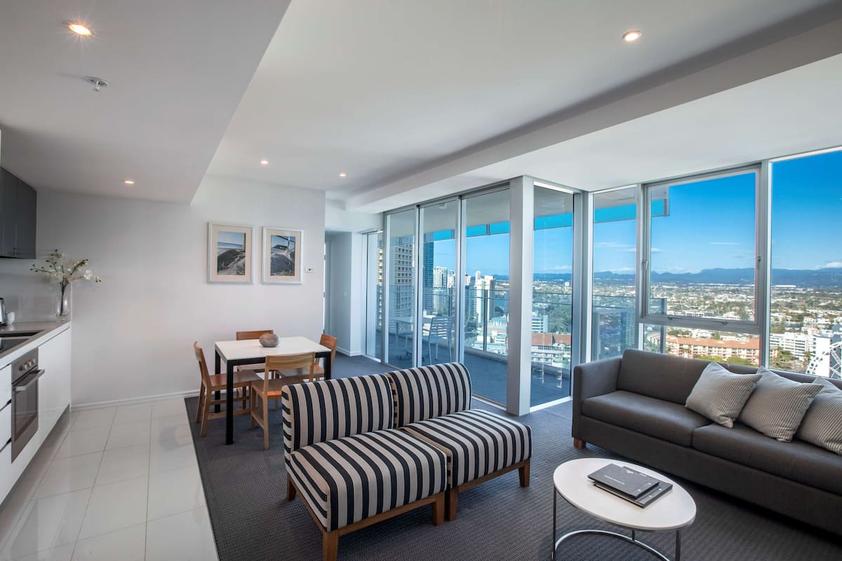 A modern apartment with a dining area, sofa, and a balcony with a city view.