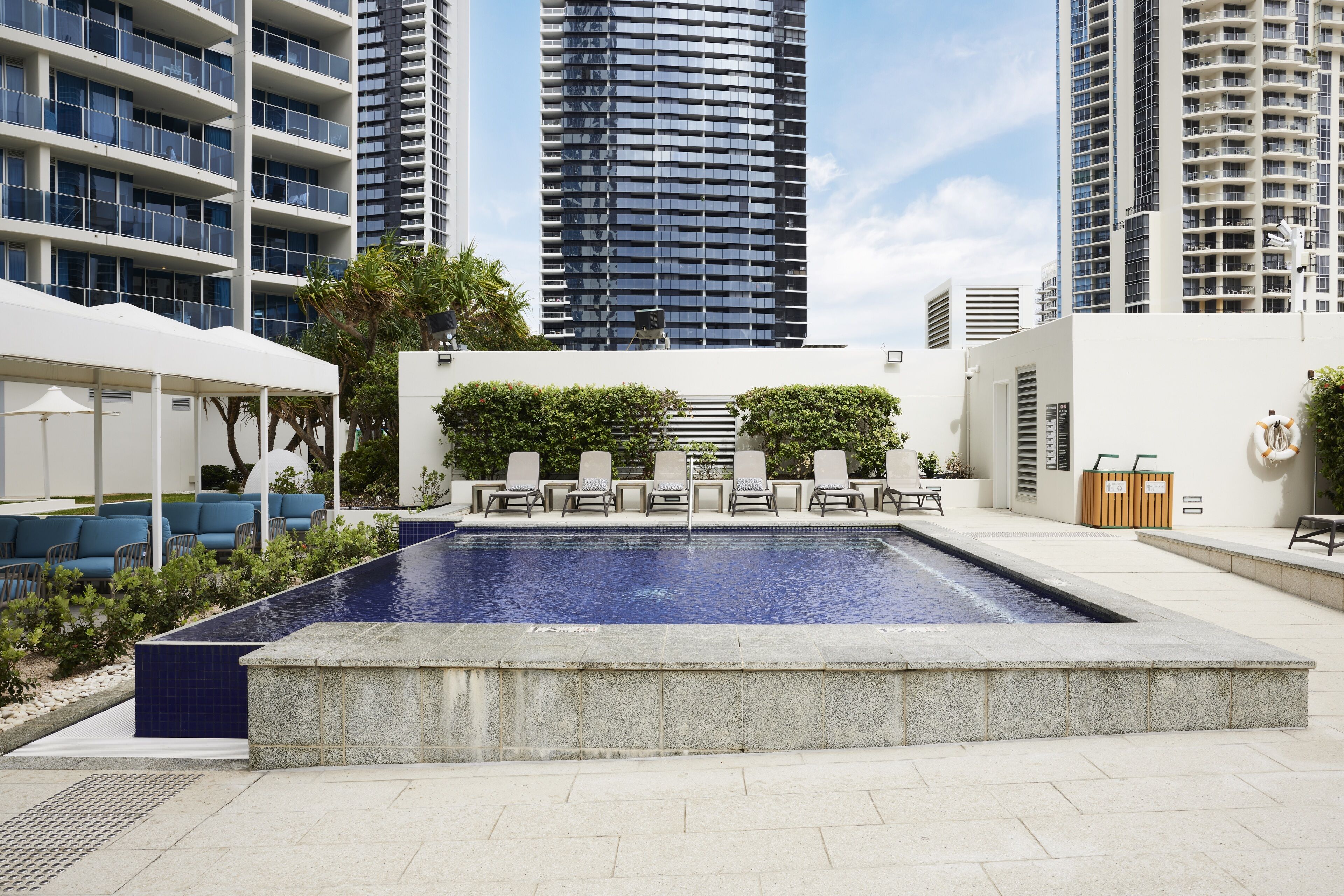 A rooftop pool with lounge chairs, surrounded by high-rise buildings.