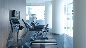 A modern gym with treadmills, elliptical machines, and a large exercise ball, featuring large windows and a minimalist design.