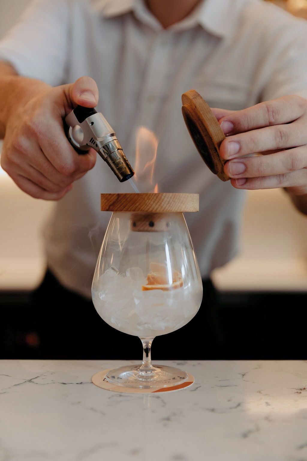 Une personne verse un liquide d’un récipient en métal dans un verre muni d’un couvercle en bois.