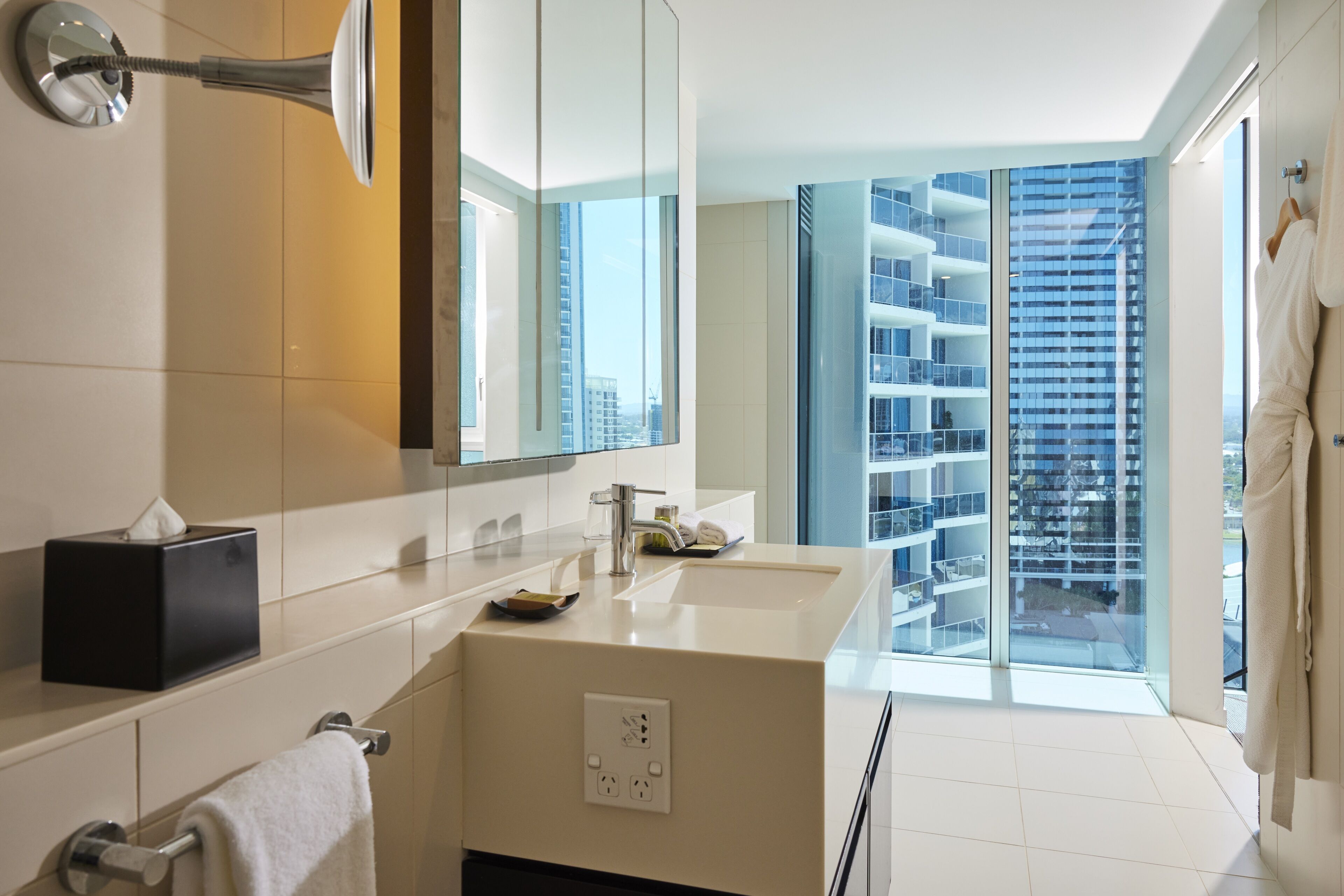 Un baño moderno con un espejo grande, un lavabo y un perchero para toallas.