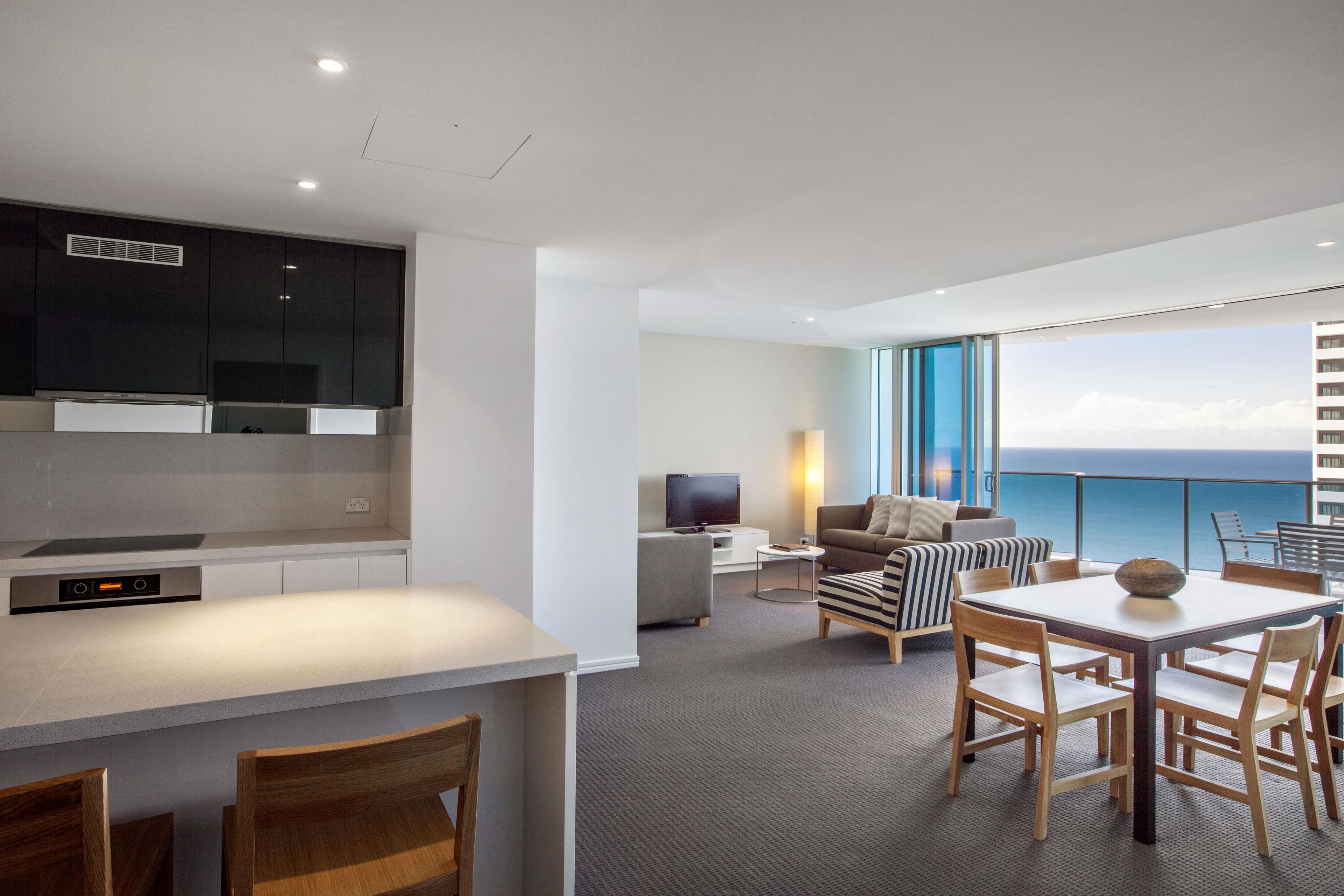 Una habitación de hotel moderna con cocina, comedor y un balcón con vistas.