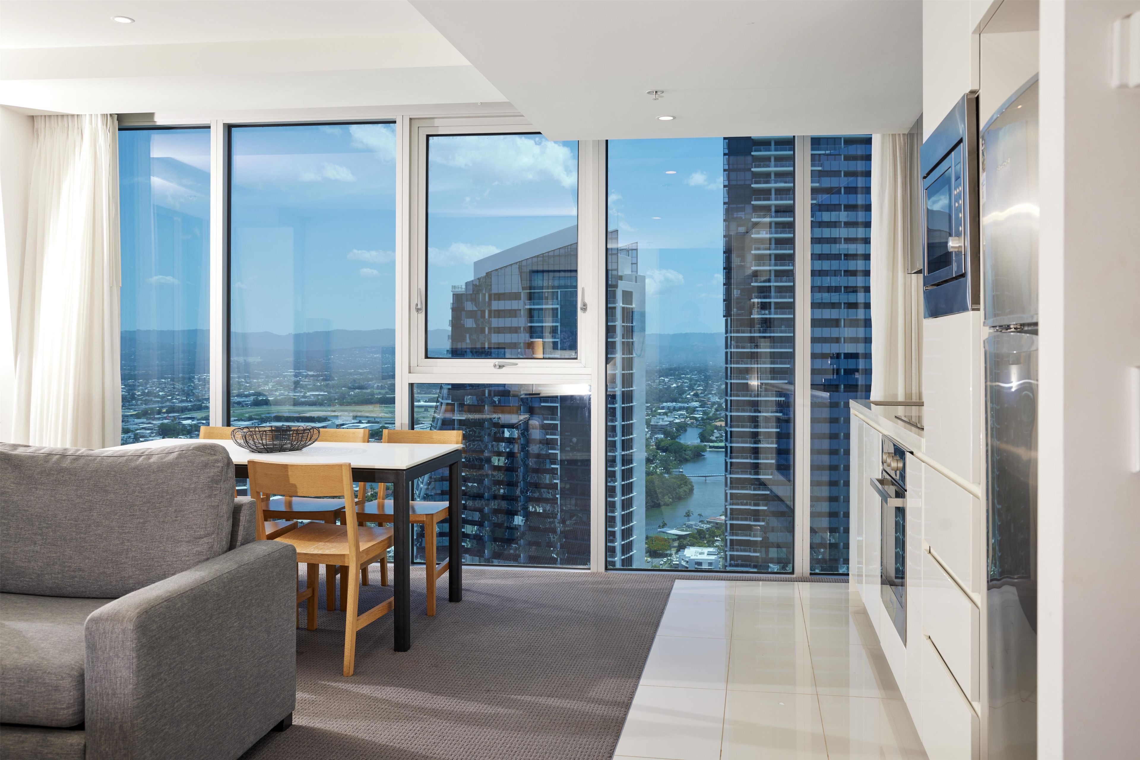 A modern living room with a dining area, large windows, and a view of a cityscape.