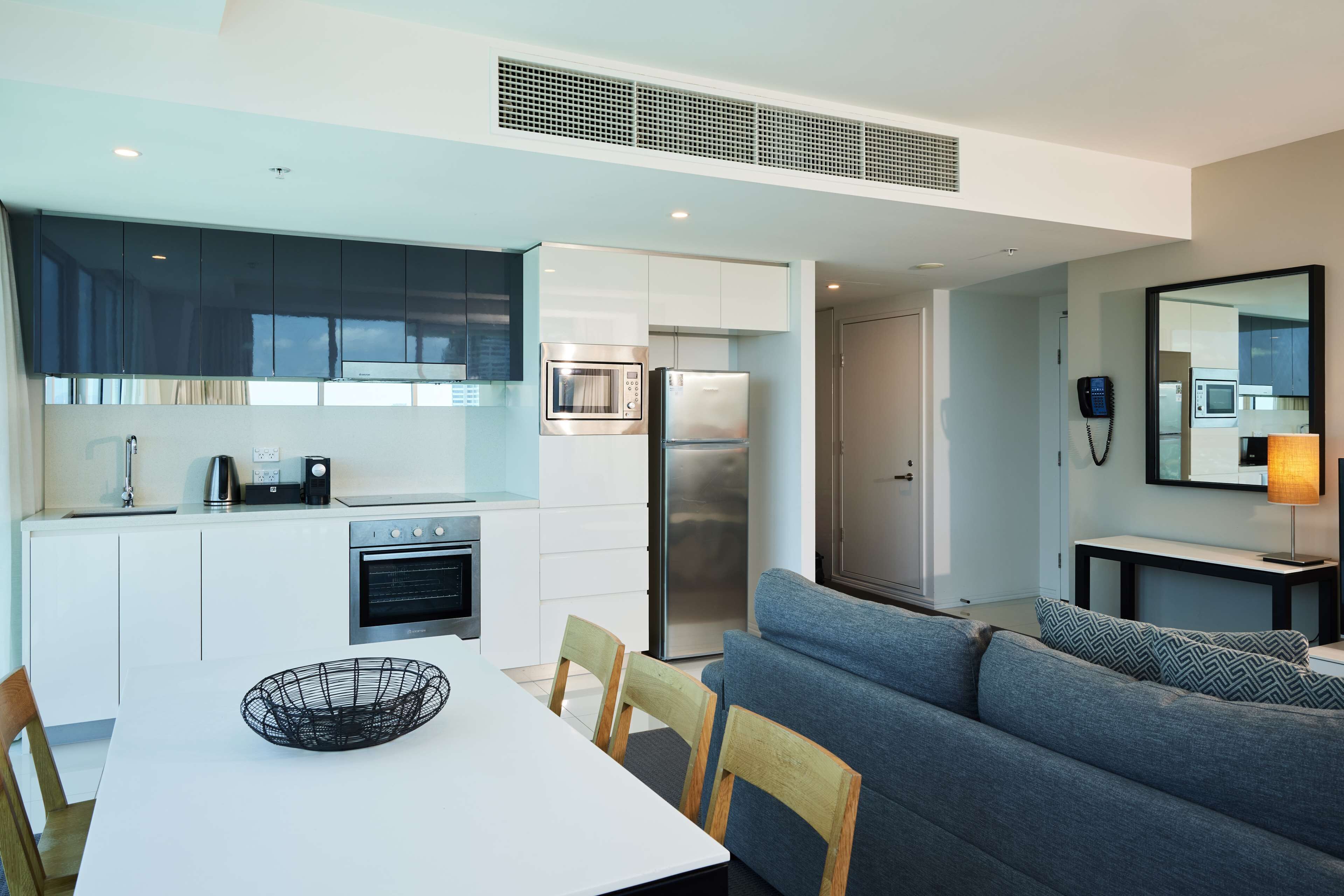 A modern kitchen with white cabinets, stainless steel appliances, and a dining area with a white table and chairs.