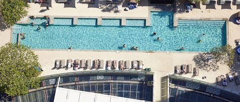 A rooftop swimming pool with multiple lanes, surrounded by lounge chairs and umbrellas.