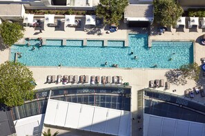 A rooftop swimming pool with multiple lanes, surrounded by lounge chairs and umbrellas.