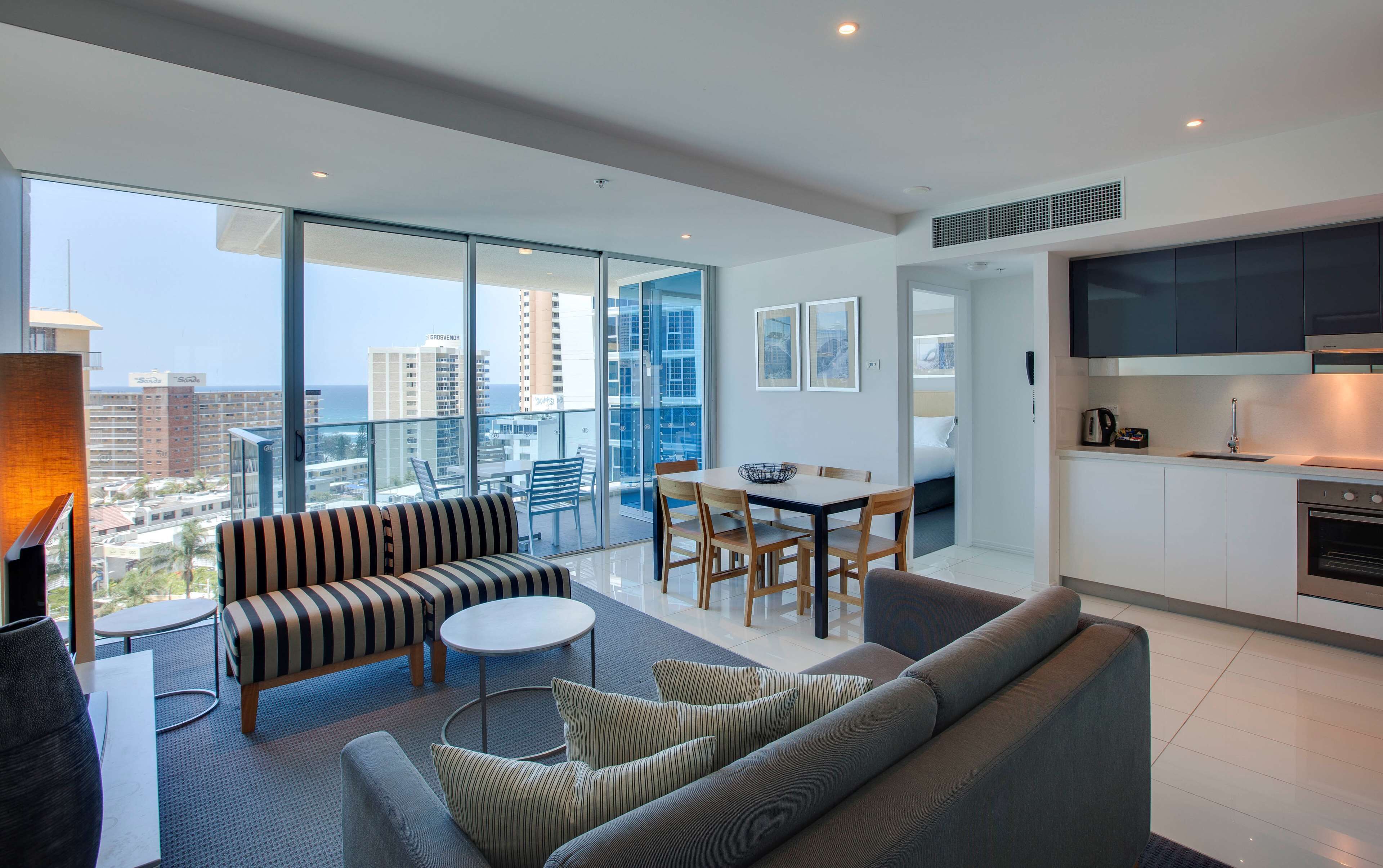 A modern apartment with a balcony, a dining area, and a kitchenette.
