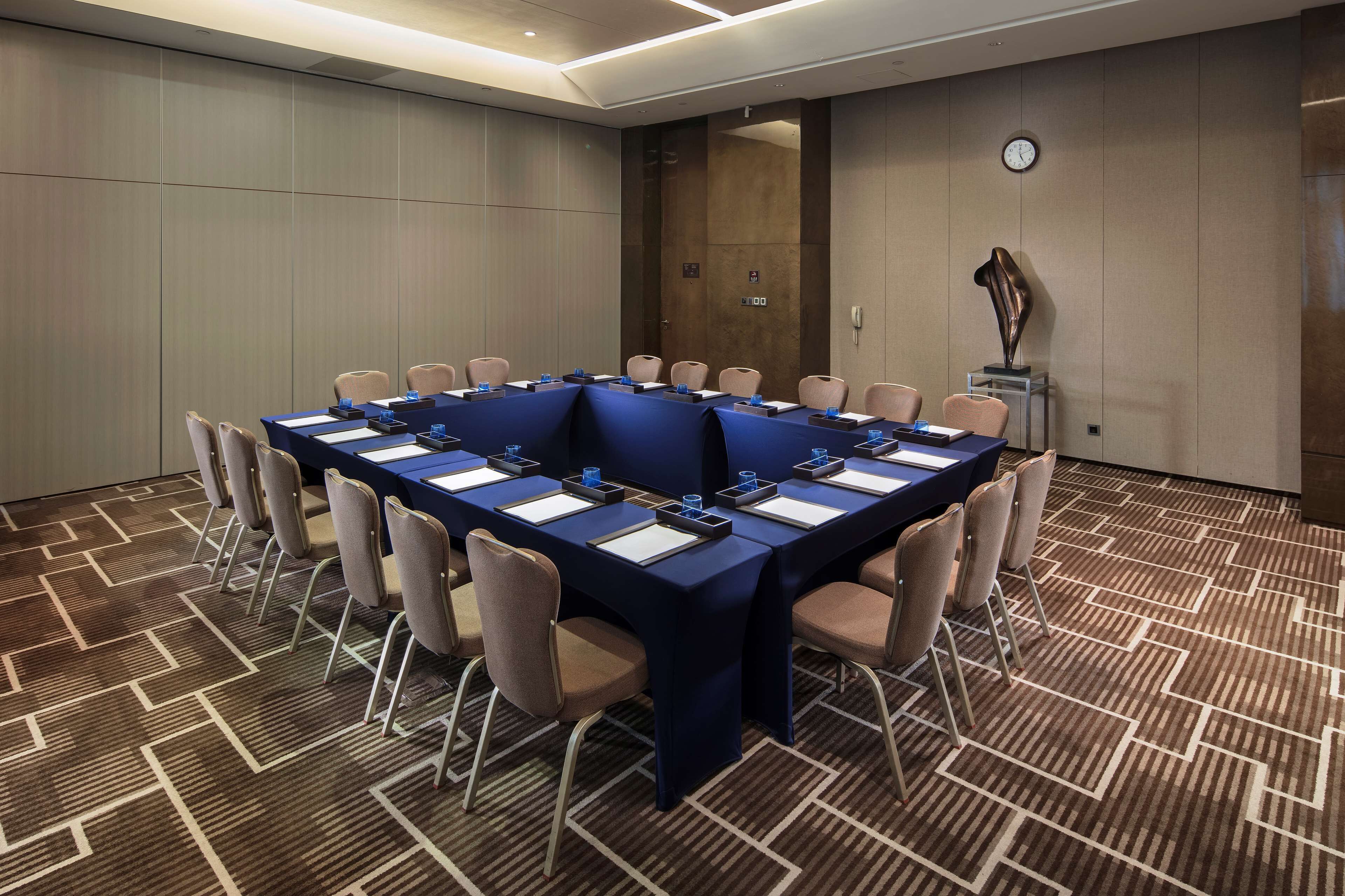 A conference room with a long table, chairs, and a clock on the wall.