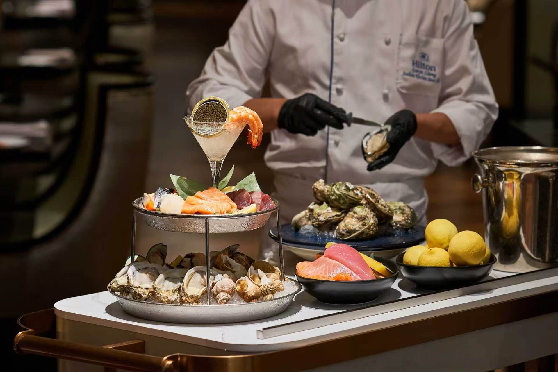 Una bandeja de mariscos con distintos tipos de pescado y mariscos, una copa de martini, y limones sobre una encimera.