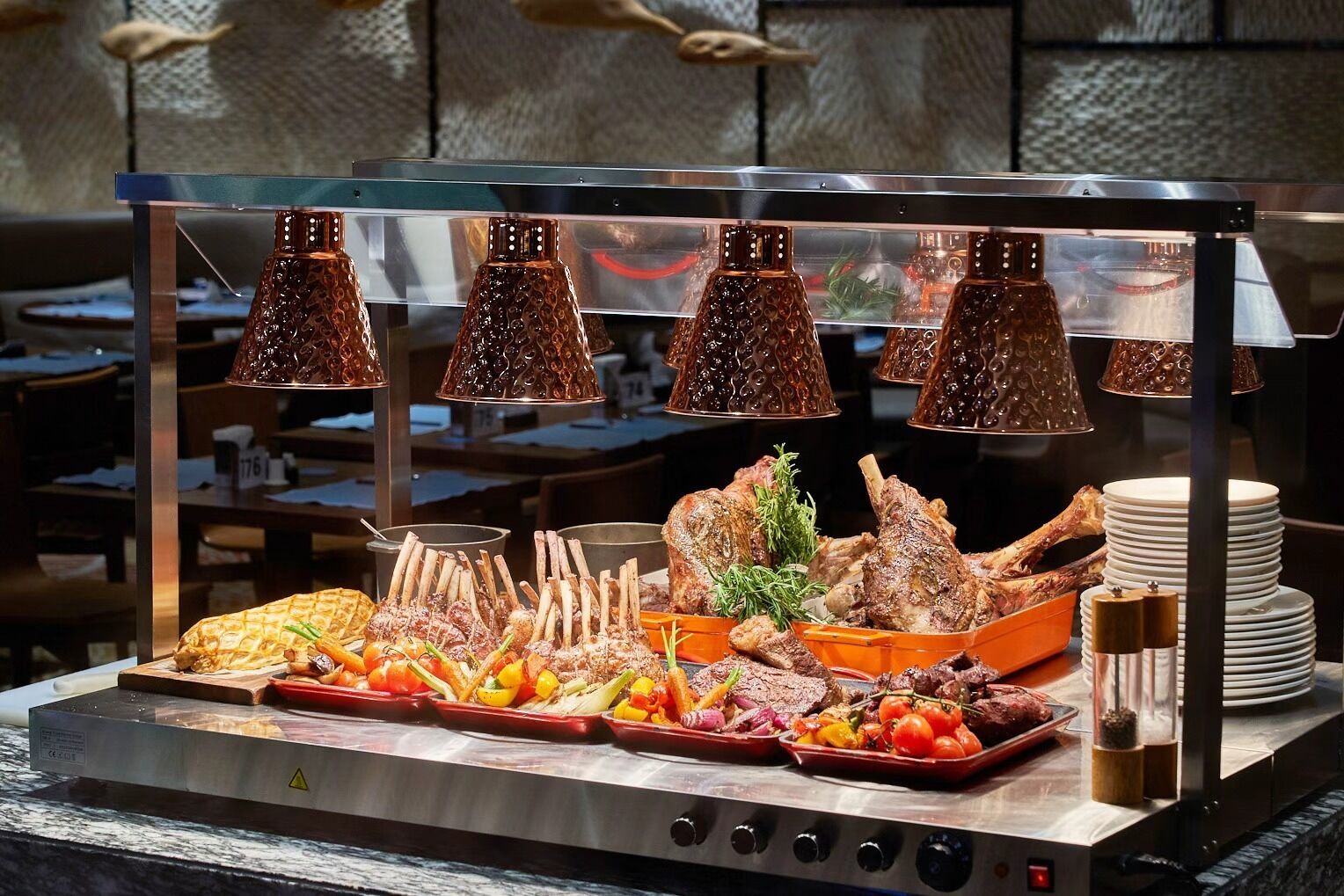 A buffet setup with various meats, vegetables, and a salad.
