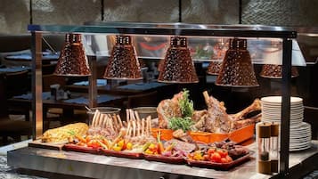 A buffet setup with various meats, vegetables, and a salad.