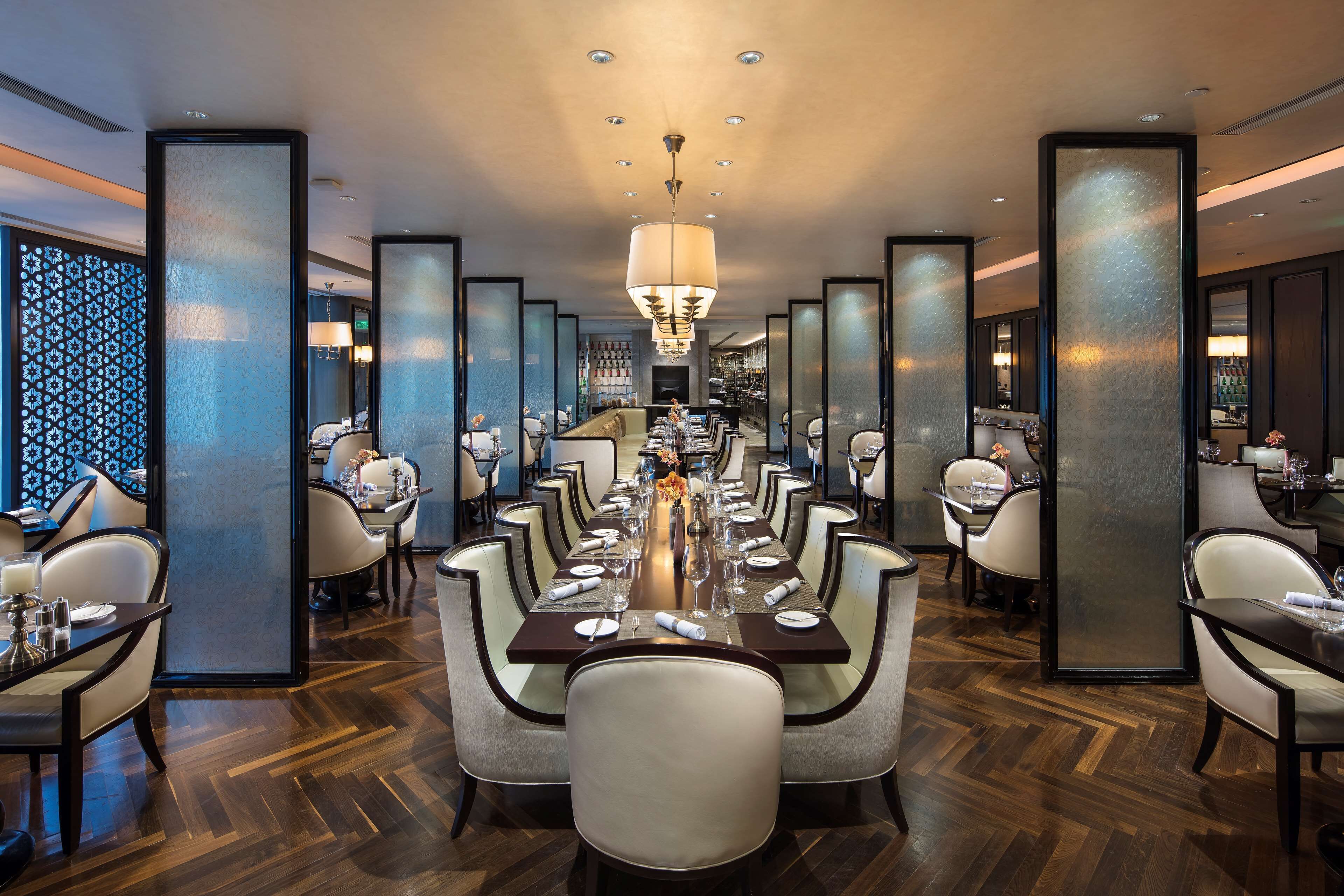 A formal dining room with a long table set for a meal, surrounded by high-backed chairs.
