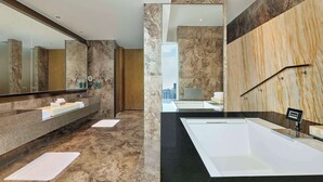 Un baño moderno con un espejo grande, dos lavamanos, una bañera y vistas a la ciudad.
