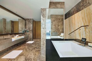 Un baño moderno con un espejo grande, dos lavamanos, una bañera y vistas a la ciudad.