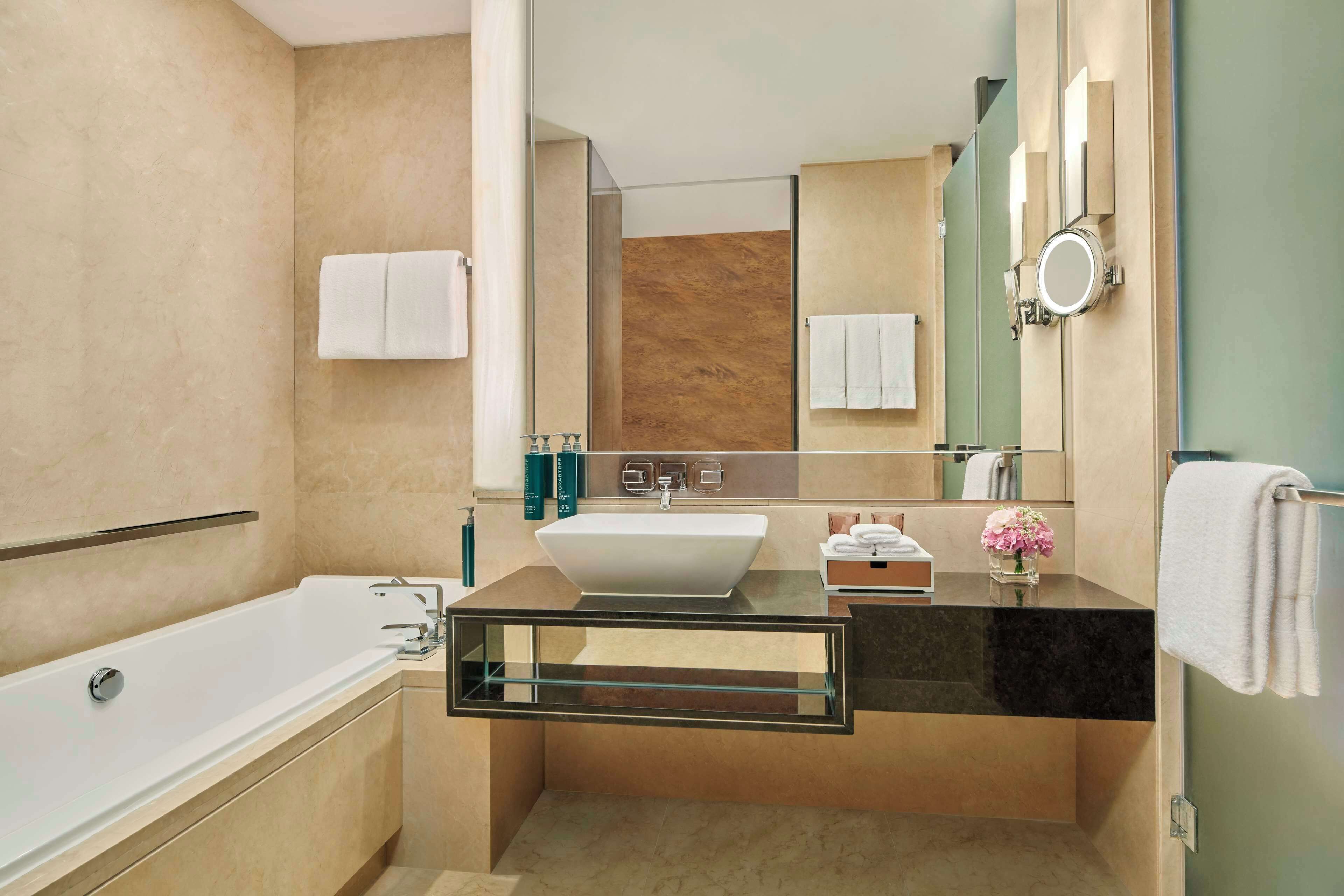 A modern bathroom with a freestanding bathtub, a large mirror, and a vanity with a sink and countertop.