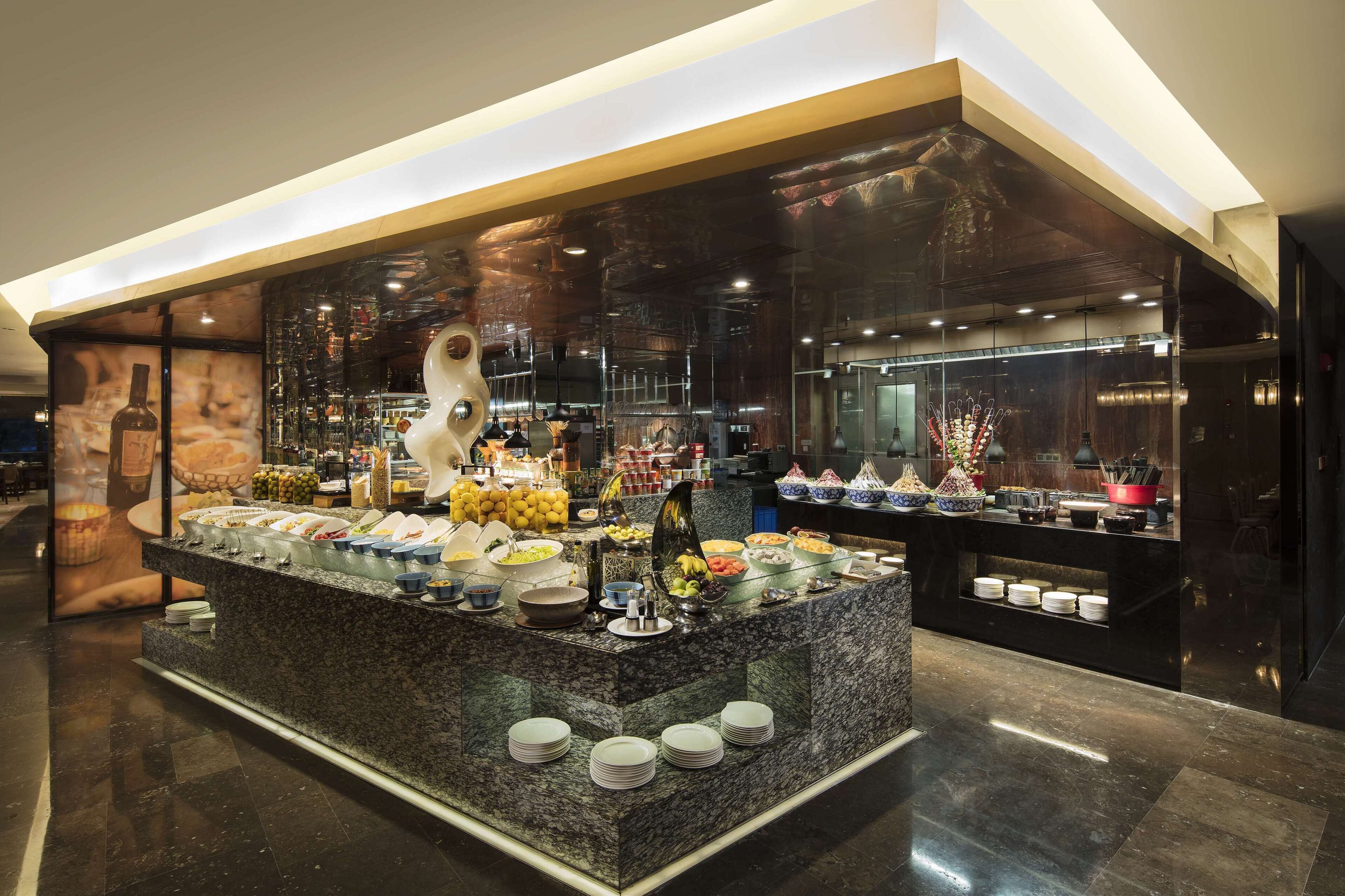 A buffet area with various food items and a central decorative sculpture.