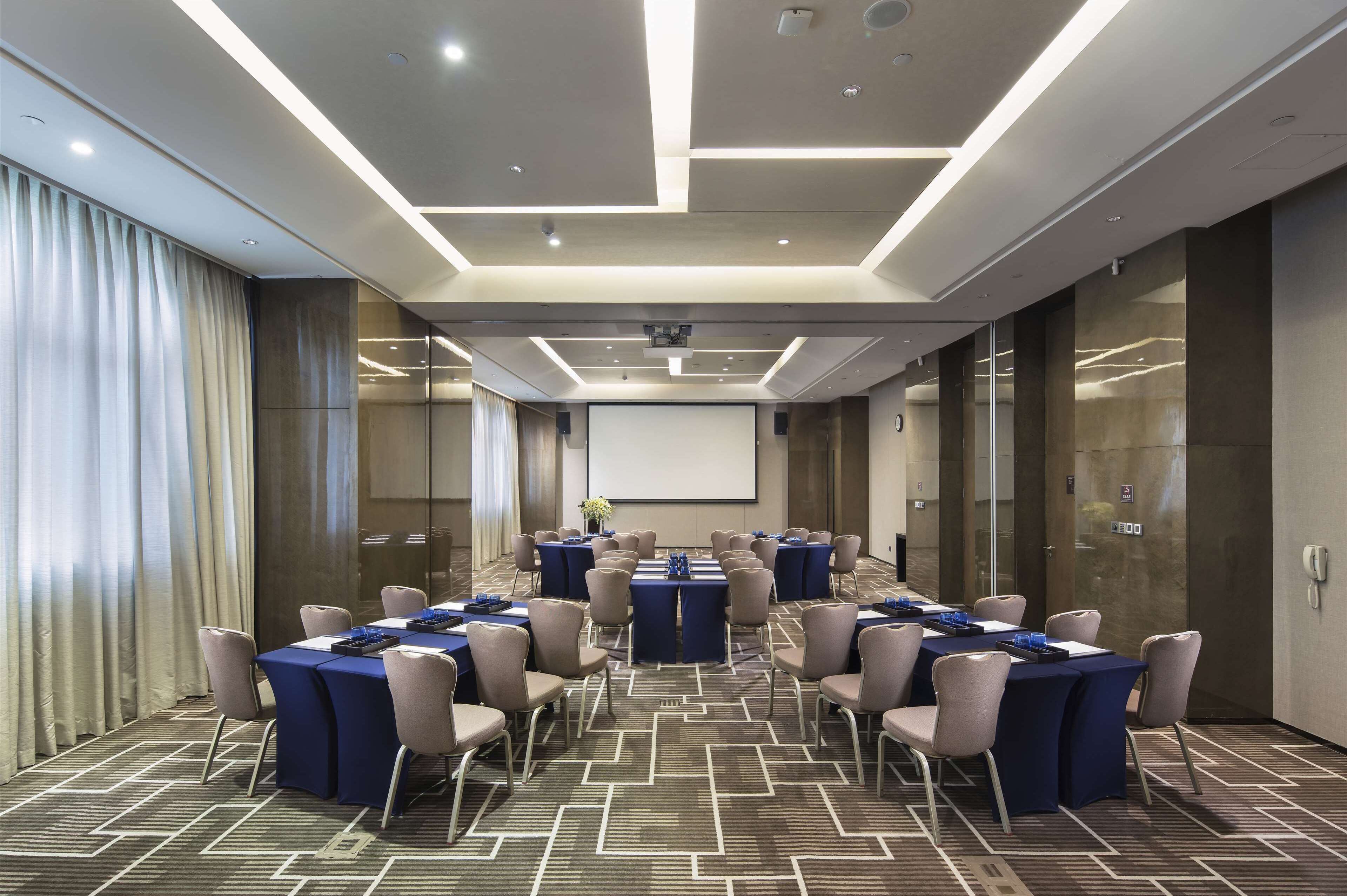 A conference room with multiple tables, chairs, and a projector screen.