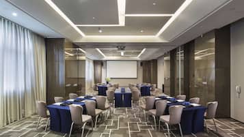 A conference room with multiple tables, chairs, and a projector screen.