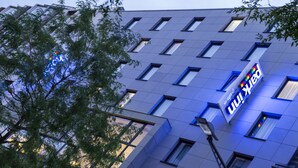 Un edificio moderno con fachada azul, varias ventanas y un letrero que dice 'Hotel Inn'.