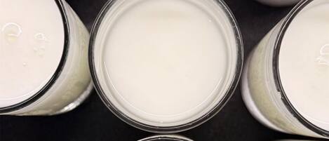Varios recipientes de vidrio con un contenido blanco, probablemente leche, dispuestos en un patrón de cuadrícula.