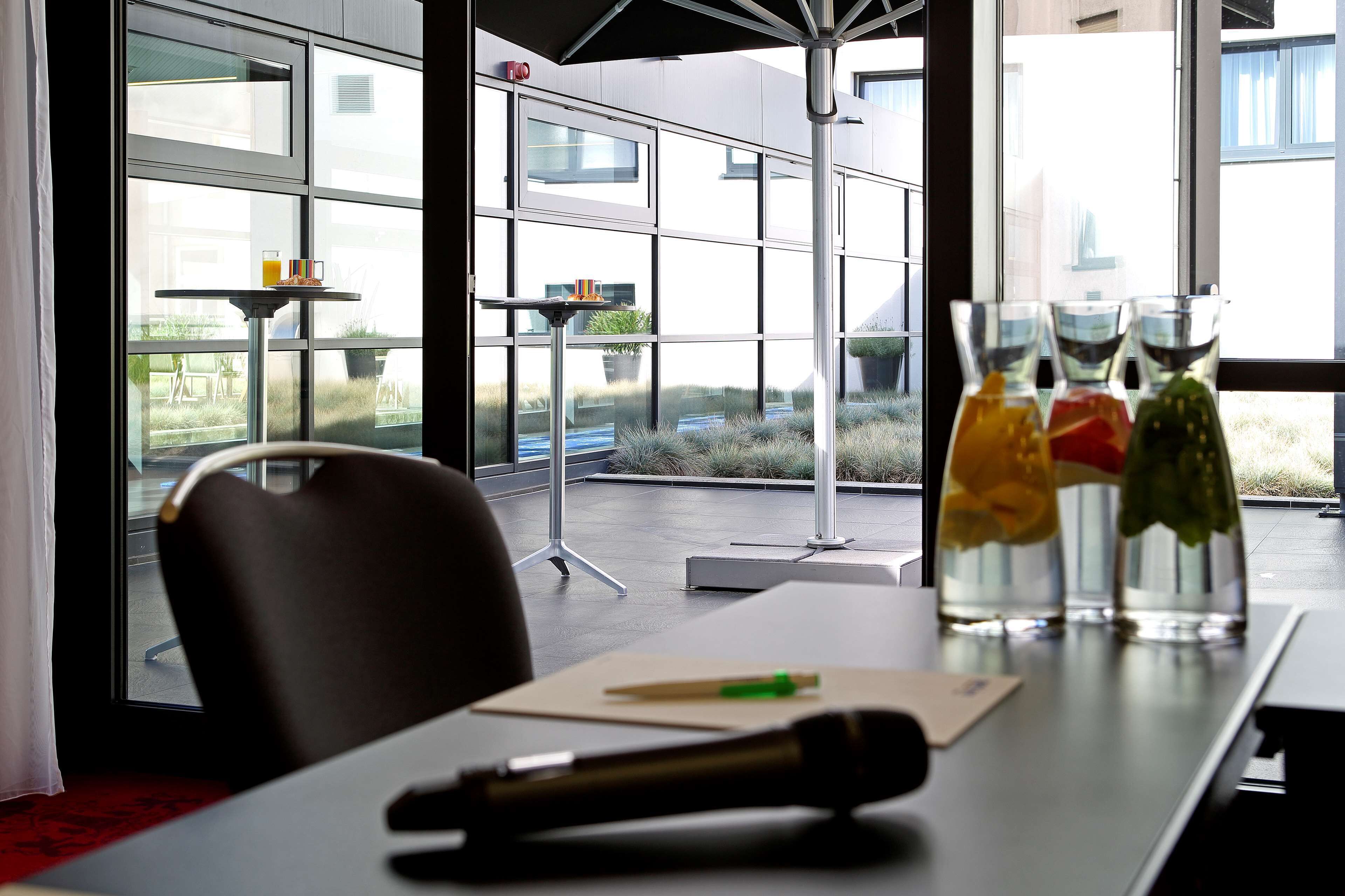 A modern office space with large windows, a table with a pen, and a glass vase with colorful objects.