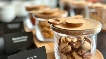 A display of Brazil nuts in a glass jar with a wooden lid, labeled 'Brazil Nuts Noix du Brésil,' on a wooden board.