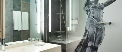 Un baño moderno con tocador de mármol, cabina de ducha de vidrio y un espejo grande.