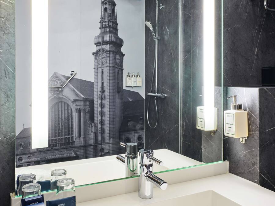 Une salle de bain moderne avec un grand miroir, une douche et un lavabo.