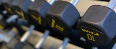 A rack of black dumbbells with yellow markings, indicating weight.