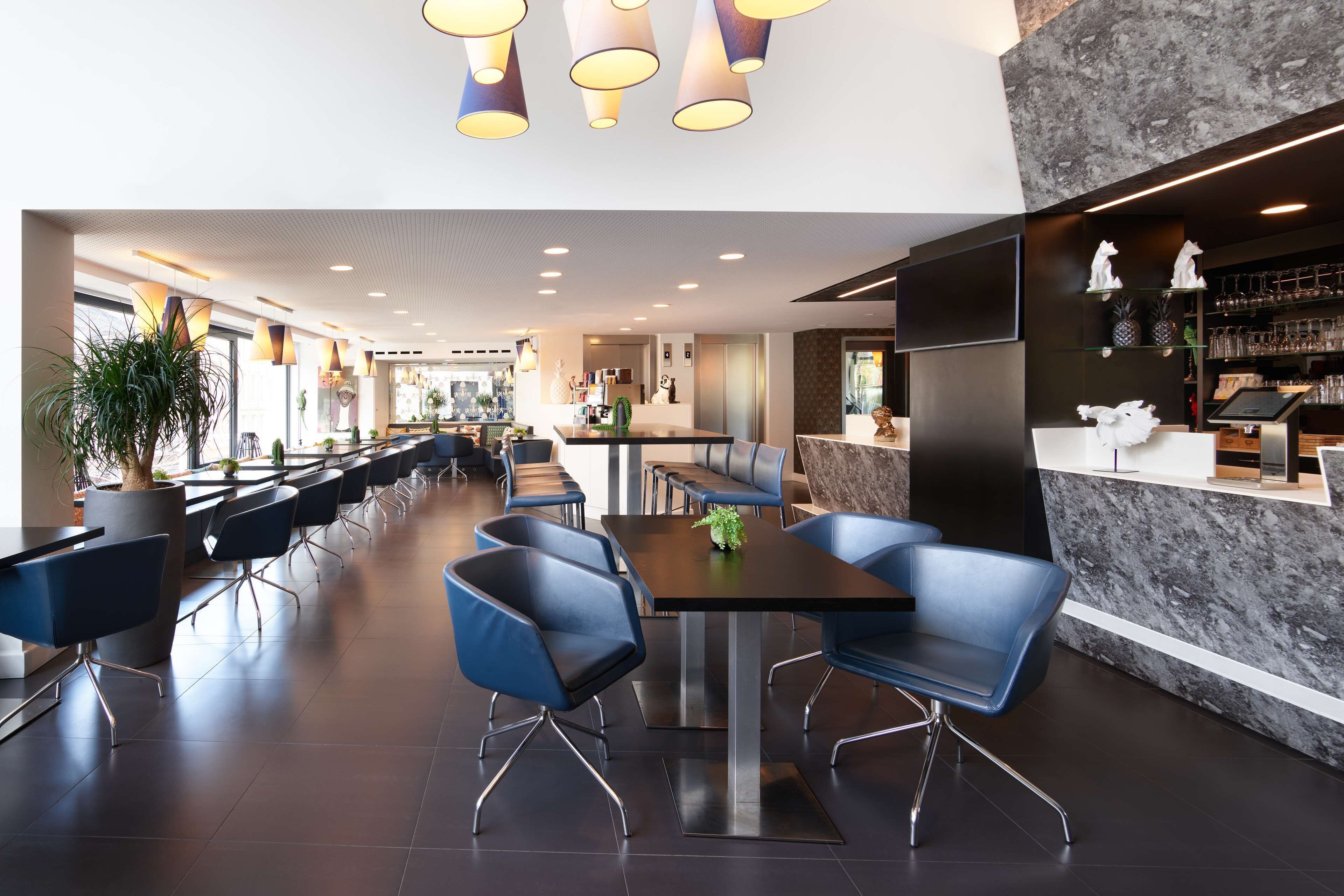 Un restaurant moderne avec un long comptoir, des chaises bleues et un mur en marbre.