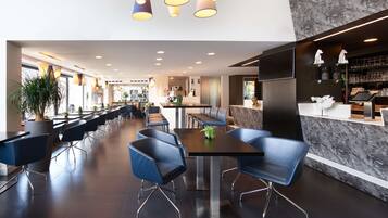 Un restaurant moderne avec un long comptoir, des chaises bleues et un mur en marbre.
