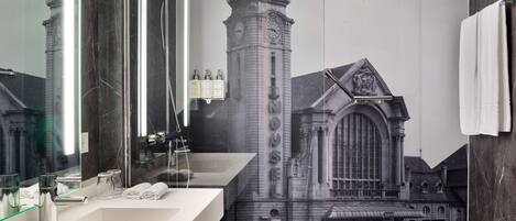 Un baño con un espejo grande, un lavamanos moderno y un perchero para toallas en la pared.
