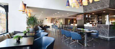 A modern hotel lobby with a seating area, a bar, and a reception desk.