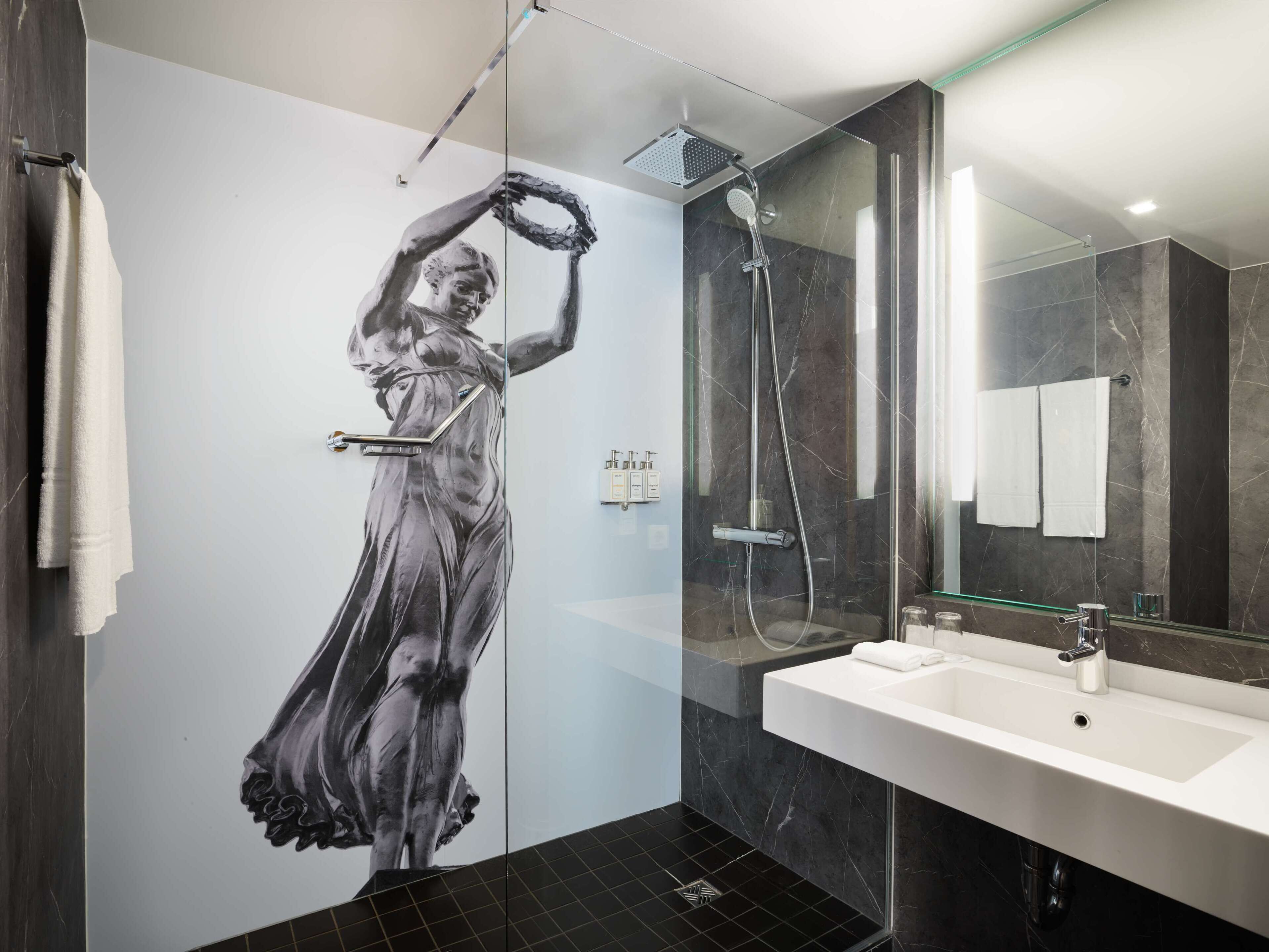 A modern bathroom with a large mirror, a shower, and a sink.