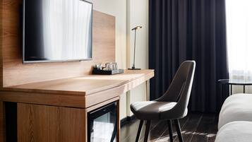 Une chambre d’hôtel avec un bureau en bois, un téléviseur à écran plat, une chaise, une table de chevet et un lit.