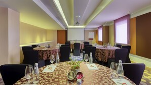 A conference room with round tables, chairs, and a projector screen. - Ibis Bengaluru Outer Ring Road (Bengaluru)
