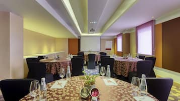 A conference room with round tables, chairs, and a projector screen.