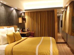 Une chambre d’hôtel avec un grand lit, un bureau avec une chaise, une télévision et un miroir.