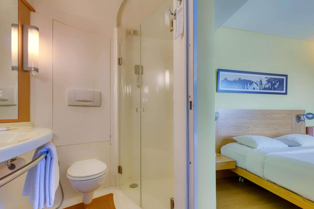 Un baño con inodoro, lavamanos y cabina de ducha de cristal.