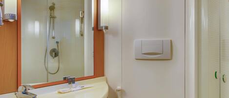 A bathroom with a sink, mirror, towel rack, shower, and a soap dispenser.