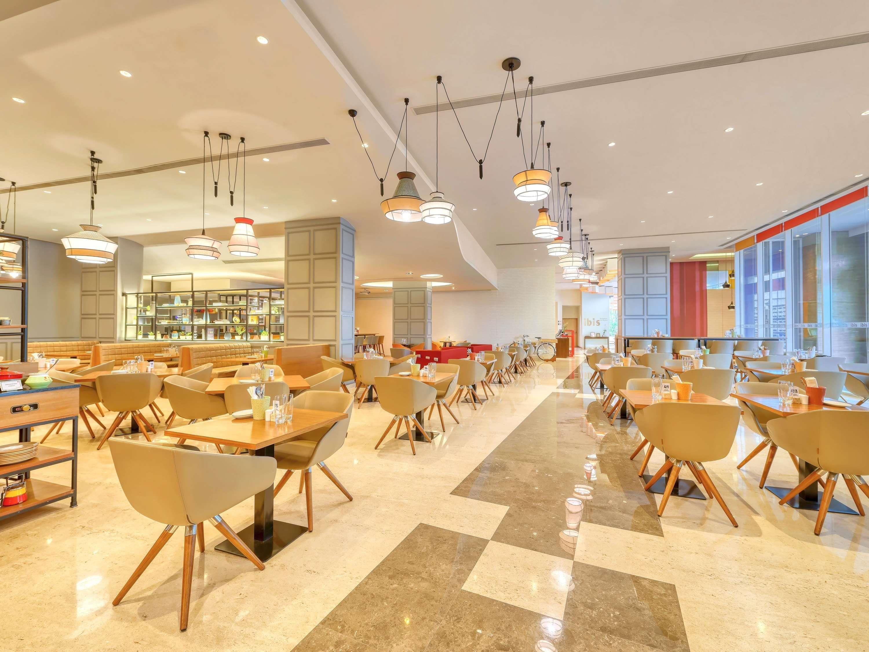 Ein geräumiges Restaurant mit mehreren Essbereichen, moderner Beleuchtung und einem sauberen, glänzenden Boden.