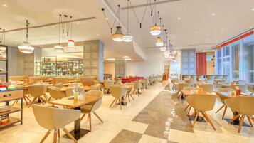 Un restaurante espacioso con varias zonas de comedor, luminarias modernas y un suelo limpio y pulido.